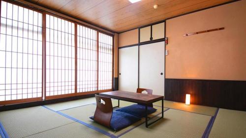 a room with a table and a chair and windows at Business Hotel Wako in Ichinomiya