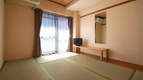 a room with a window with a television and a table at Business Hotel Wako in Ichinomiya