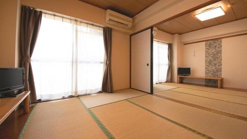 a living room with a tv and large windows at Business Hotel Wako in Ichinomiya