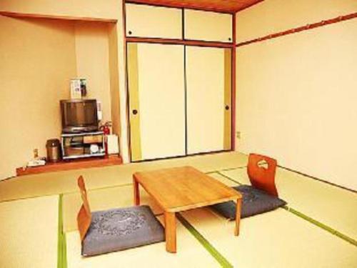a room with a wooden table and chairs in a room at Business Hotel Wako in Ichinomiya