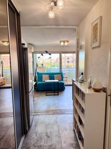 un salon avec un canapé bleu et une table dans l'établissement Le Scarlett- Confort à Palavas-Plage à proximité, Terrasse, Piscine et Clim -LaConciergerieByNina, à Palavas-les-Flots