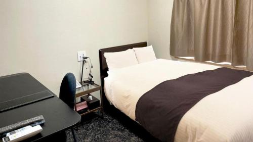 a bedroom with a bed and a desk with a printer at Business Hotel Wako in Ichinomiya