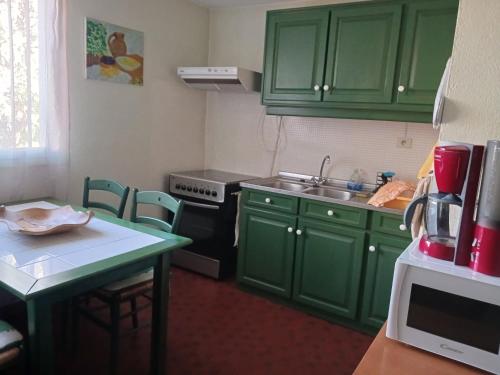 une cuisine avec des placards verts et une petite table dans l'établissement Appart Rez de Jardin Chez Anne, à Vernet-les-Bains