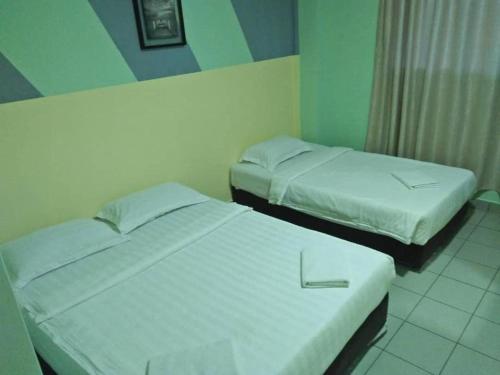 two beds in a small room at Hotel Tuaran in Kota Kinabalu