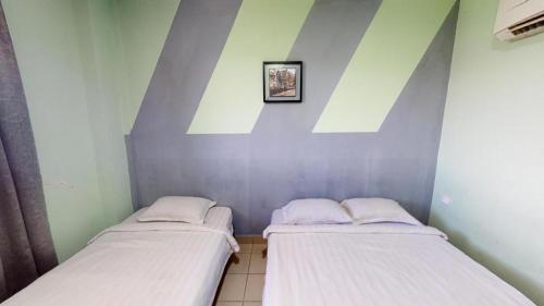 two twin beds in a room with a roof at Hotel Tuaran in Kota Kinabalu