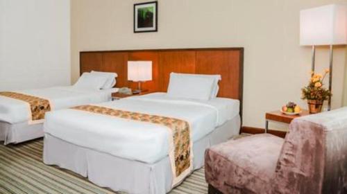 a hotel room with two beds and a chair at RH Hotel Sibu in Sibu