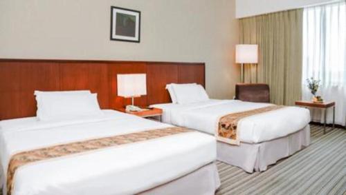 a hotel room with two beds and a chair at RH Hotel Sibu in Sibu