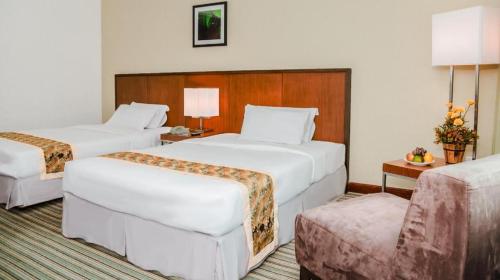 a hotel room with two beds and a couch at RH Hotel Sibu in Sibu