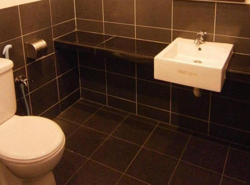 a bathroom with a white toilet and a sink at Hotel Kawan in Kampar