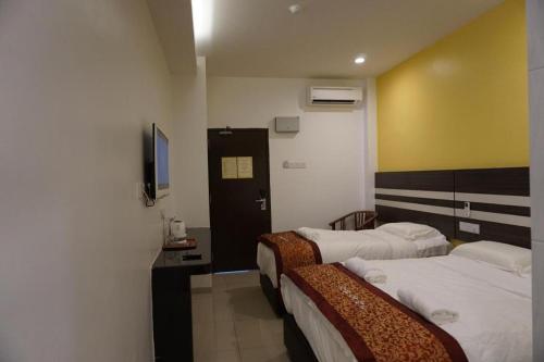 a hotel room with two beds and a television at Hotel Kristal in Seri Iskandar