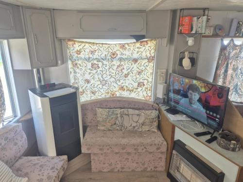 a small living room with a tv and a couch in a rv at Le Petit Logis in Philippeville