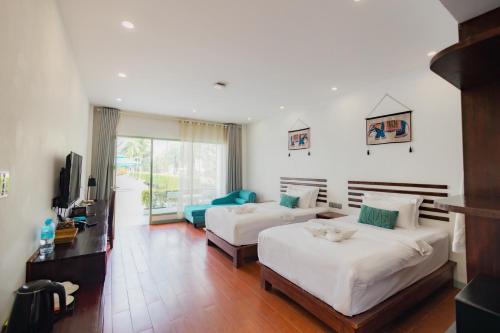 a hotel room with two beds and a television at Amanda Hotel阿曼达酒店 in Luang Prabang