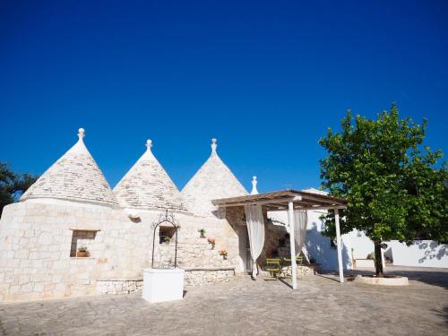 a stone building with a canopy and a tree at Relais Trulli Le Icone in Ostuni