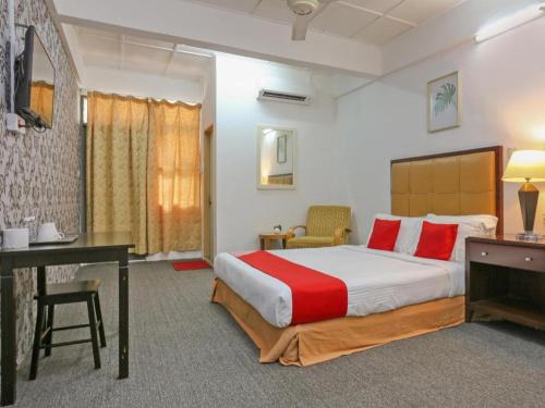 a hotel room with a bed and a desk at OYO 89922 The Sarina Hotel & Cafe in Jeli