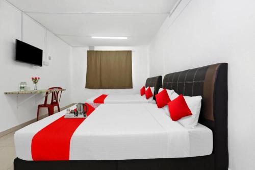 Un dormitorio con una cama grande con almohadas rojas. en OYO 90873 Travellers Inn, en Kampong Kijang