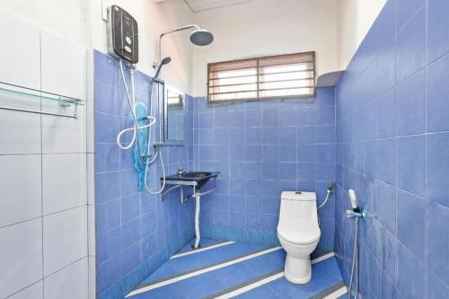 y baño de azulejos azules con aseo y ducha. en OYO 90873 Travellers Inn, en Kampong Kijang