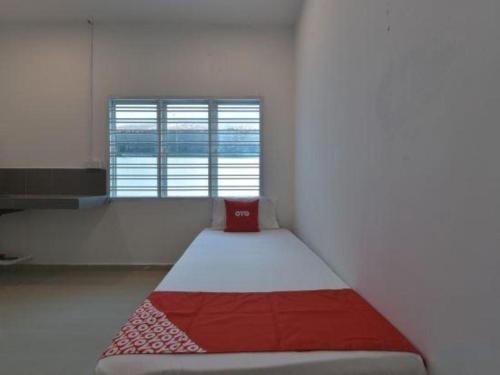 ein Bett in einem Zimmer mit Fenster in der Unterkunft OYO 90889 Narasindo Cottage in Kuala Lumpur