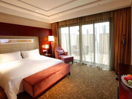 a hotel room with a bed and a chair and a window at Suzhou Qingshan Conference Center in Suzhou