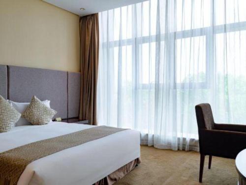a bedroom with a bed and a chair and a large window at Suzhou Qingshan Conference Center in Suzhou