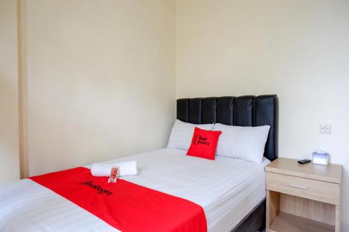 a bedroom with a bed with a red blanket on it at RedDoorz Syariah near Purwosari Train Station in Solo