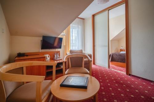 a hotel room with a desk and a television at Kompleks Antałówka Termy & Med in Zakopane