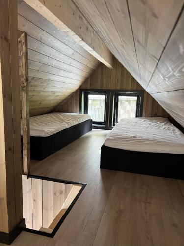 two beds in a room with wooden walls at Flåm Minisuite in Aurland