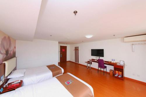 a bedroom with two beds and a desk with a television at PAI Hotels·Shijiazhuang Development Zone Tianshan Science and Technology Park in Shijiazhuang