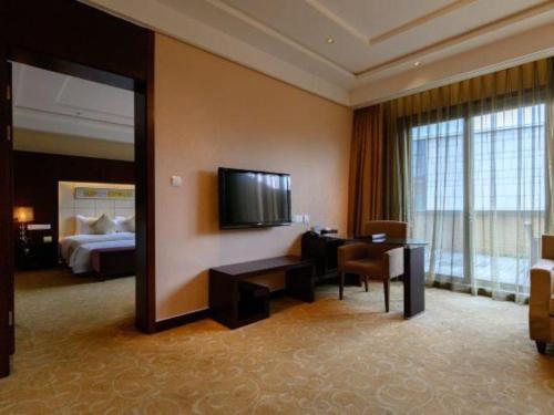 a hotel room with a bed and a desk and a television at Suzhou Qingshan Conference Center in Suzhou