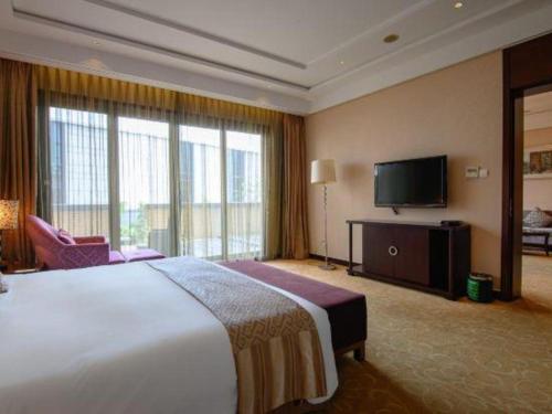 a hotel room with a large bed and a flat screen tv at Suzhou Qingshan Conference Center in Suzhou