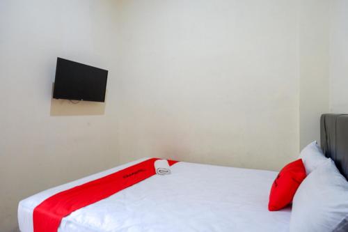 a bedroom with a bed with a tv on the wall at RedDoorz Syariah near Purwosari Train Station in Solo