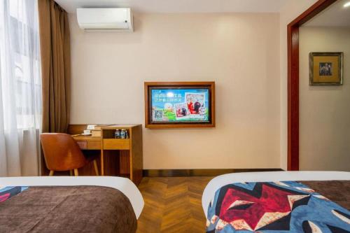 a room with two beds and a desk and a television at James Joyce Coffetel·Lijiang Old Town Centeral in Lijiang