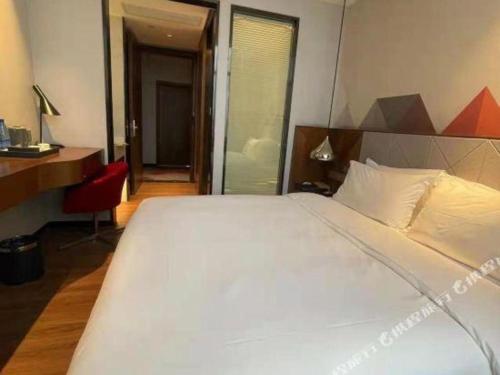 a bedroom with a large white bed and a desk at City Comfort Inn Qianjiang Longxiacheng in Qianjiang