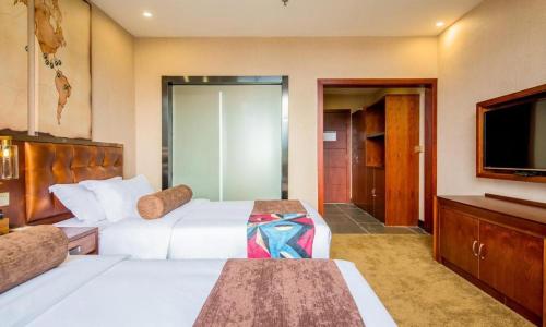 a hotel room with two beds and a flat screen tv at James Joyce Coffetel·Lijiang Old Town Centeral in Lijiang