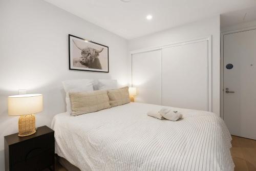 a white bedroom with a bed and a lamp at WLG CBD 1BR - Luxe Hyde Lane Stay with Amenities in Wellington