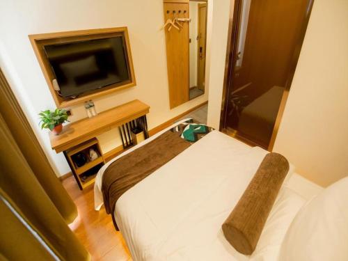 a hotel room with a bed and a television at James Joyce Coffetel Harbin Central Street in Harbin