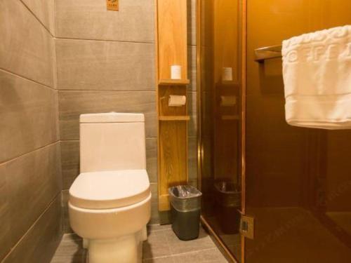 a bathroom with a toilet and a shower with towels at James Joyce Coffetel Harbin Central Street in Harbin