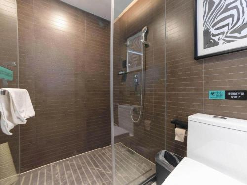 a bathroom with a glass shower with a toilet at Xana Hotelle Zhuhai Gongbei Port in Zhuhai