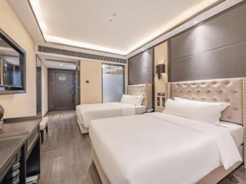 a hotel room with two beds and a television at Xana Hotelle Zhuhai Gongbei Port in Zhuhai