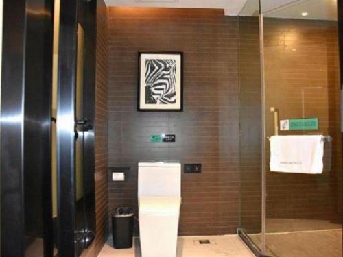 a bathroom with a glass shower and a tile wall at Xana Hotelle Zhuhai Gongbei Port in Zhuhai