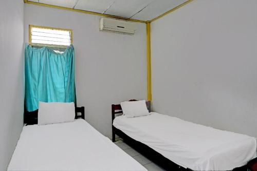 two beds in a room with a window at Hotel O Penginapan Aina Syariah in Rantaupanjang