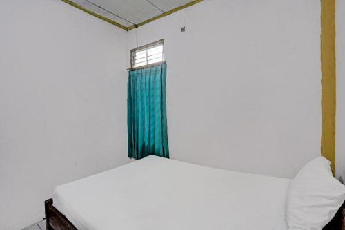 a bed in a room with a window at Hotel O Penginapan Aina Syariah in Rantaupanjang