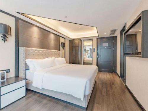 a bedroom with a large white bed and a kitchen at Xana Hotelle Zhuhai Gongbei Port in Zhuhai