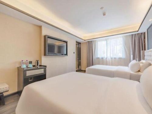 a hotel room with two beds and a television at Xana Hotelle Zhuhai Gongbei Port in Zhuhai