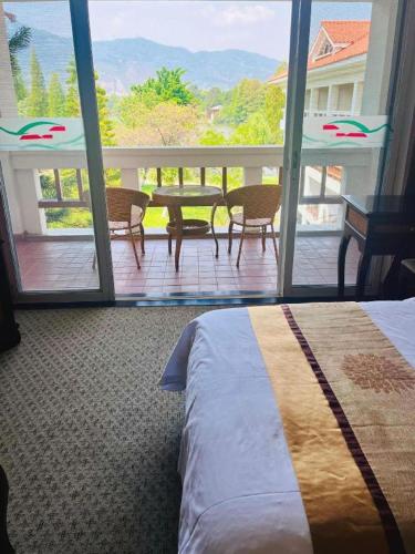 a bedroom with a bed and a balcony with a table and chairs at Kunming Dianchi Garden Hotel & Spa in Kunming