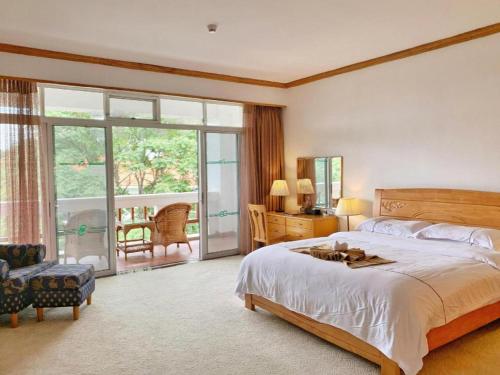 a bedroom with a large bed and a balcony at Kunming Dianchi Garden Hotel & Spa in Kunming