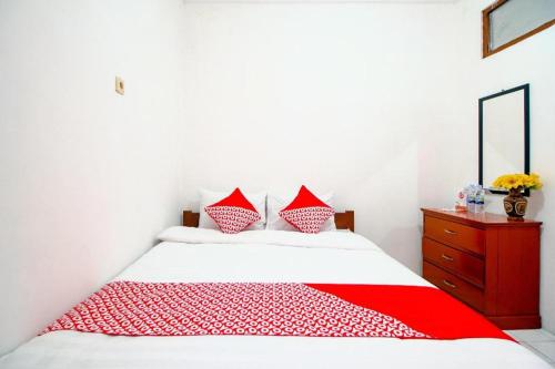 a bedroom with a red and white bed and a dresser at Super OYO 1788 House 24 in Yogyakarta
