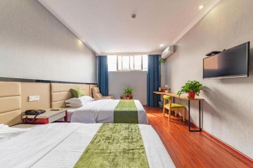 a hotel room with two beds and a flat screen tv at GreenTree Inn Yancheng Dongtai West Wanghai Road Shell Hotel in Dongtai