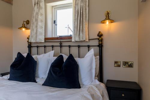 a bedroom with a bed with blue pillows and a window at Country Cottage with Hot Tub - pre-heated for your arrival in Buxton