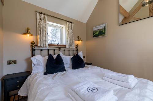 a bedroom with a bed with white sheets and pillows at Country Cottage with Hot Tub - pre-heated for your arrival in Buxton