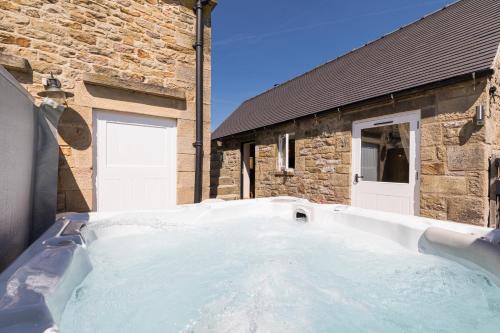 a bath tub in front of a stone house at Country Cottage with Hot Tub - pre-heated for your arrival in Buxton